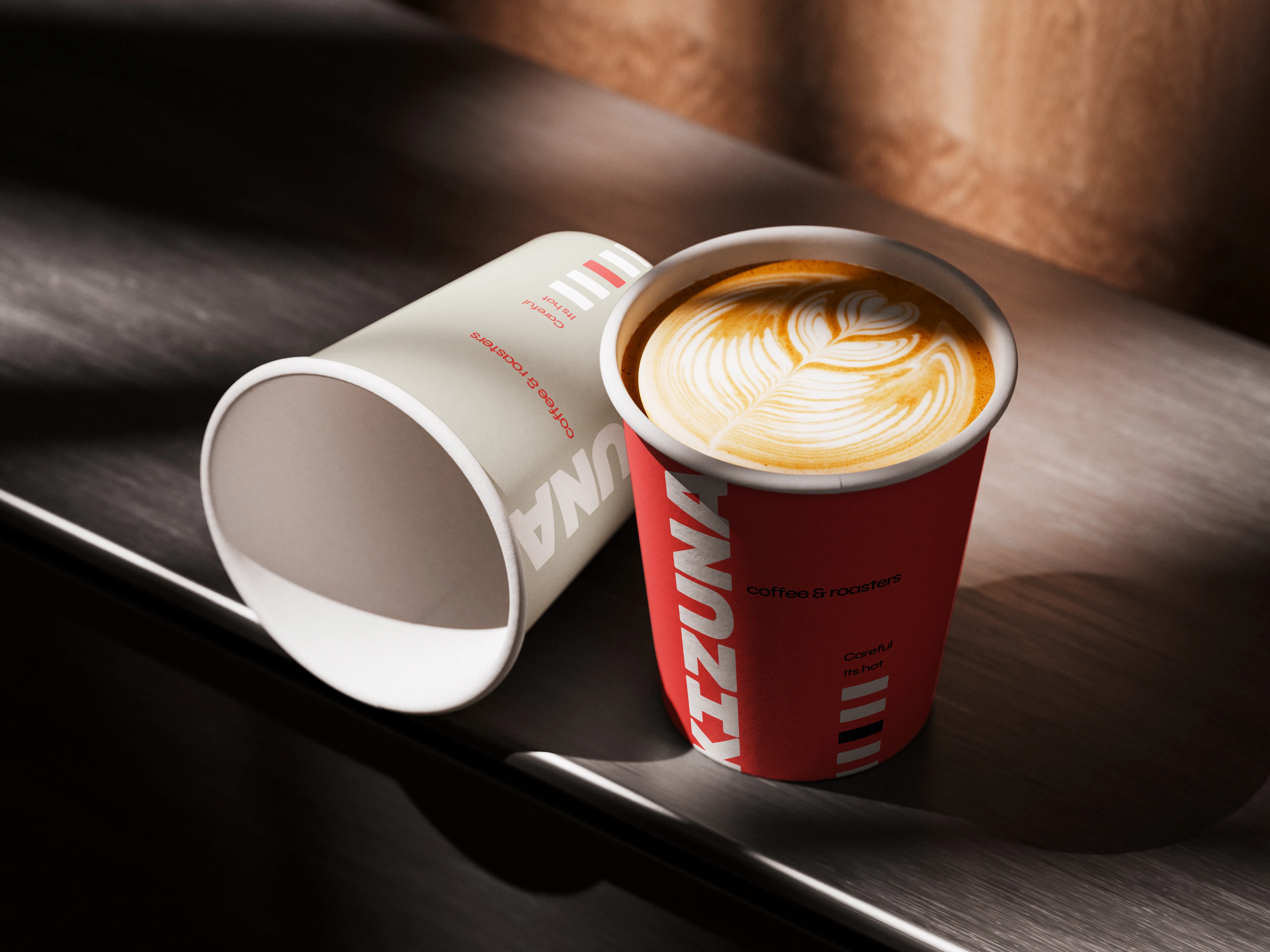 Vaso take-away Kizuna en sus dos versiones, crema y roja, sobre una barra oscura